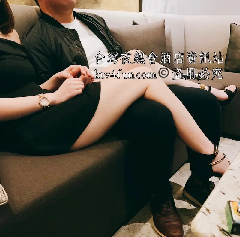 皇家會所酒店,包廂內,一位小姐穿著黑色短禮服,並把雙腿跨在男客人腿上。